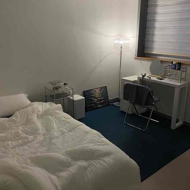 ホワイトの壁と深いブルーのカーペットが特徴の寝室、大きなベッドとコンソールテーブルが落ち着いた雰囲気を演出している