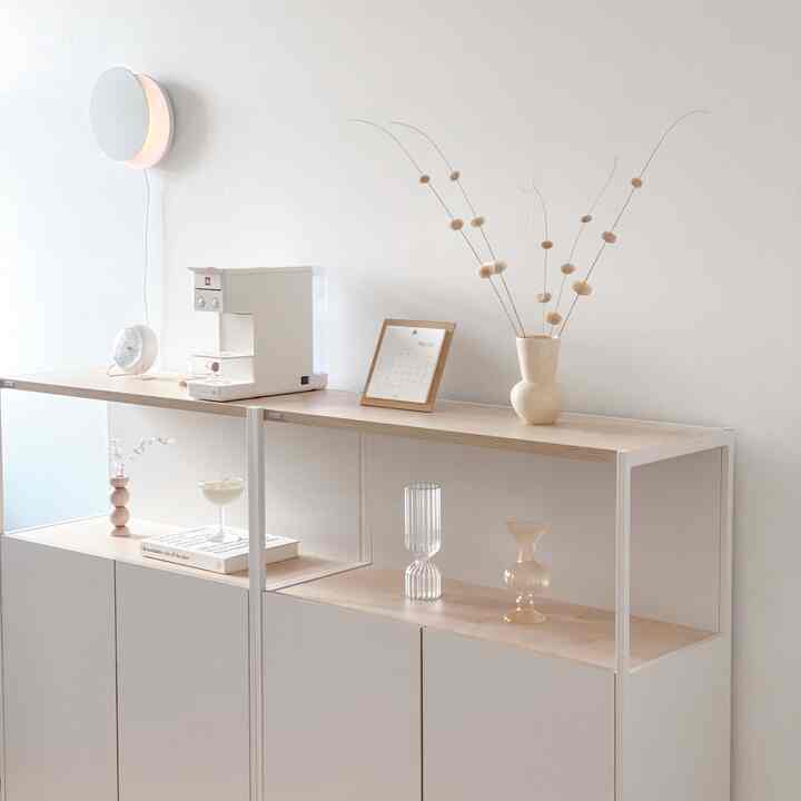 A white and natural color toned study featuring a Desk storage unit, moon mood light, coffee machine, and various objets with a clean, cozy atmosphere