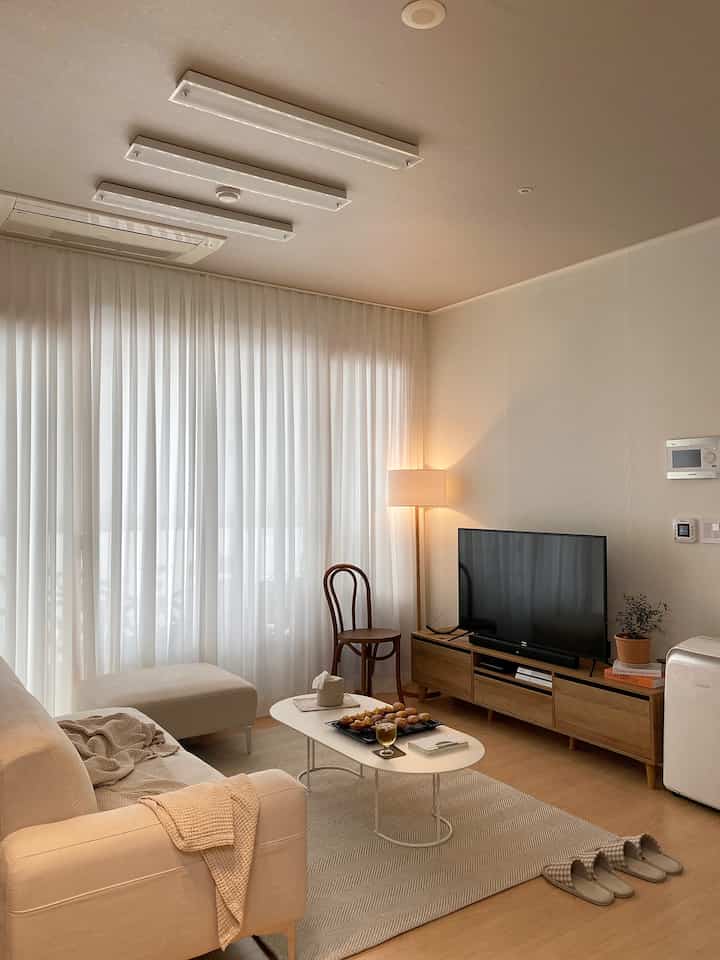 Beige-toned living room featuring sofa and TV stand with warm and cozy atmosphere