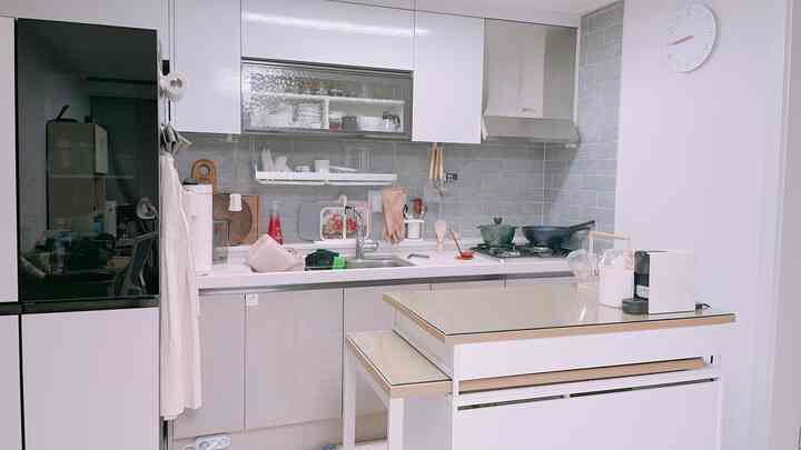 White and gray toned kitchen featuring Hanssem island table, Objet refrigerator, and various neatly arranged kitchen utensils in a modern space