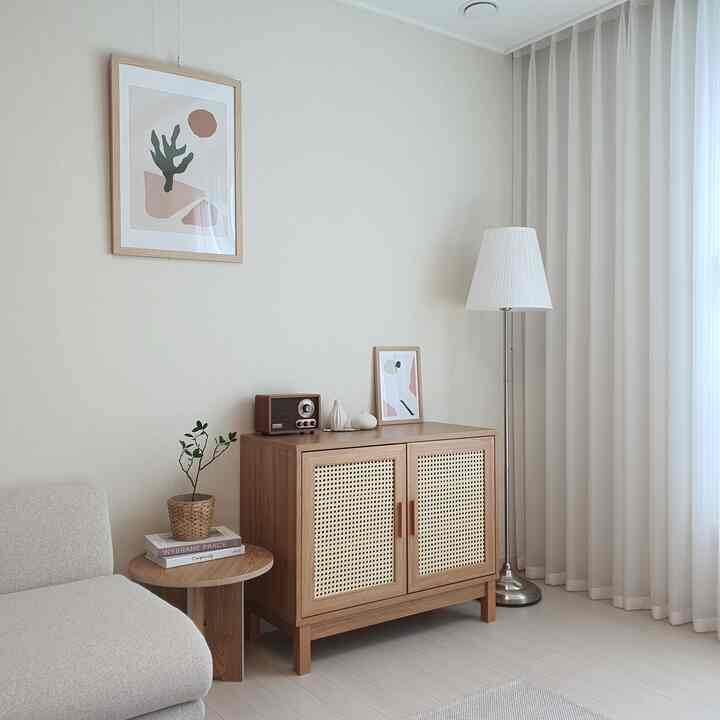 Beige-toned living room featuring wood-tone cabinet, white curtains, and floor lamp with a cozy home cafe atmosphere