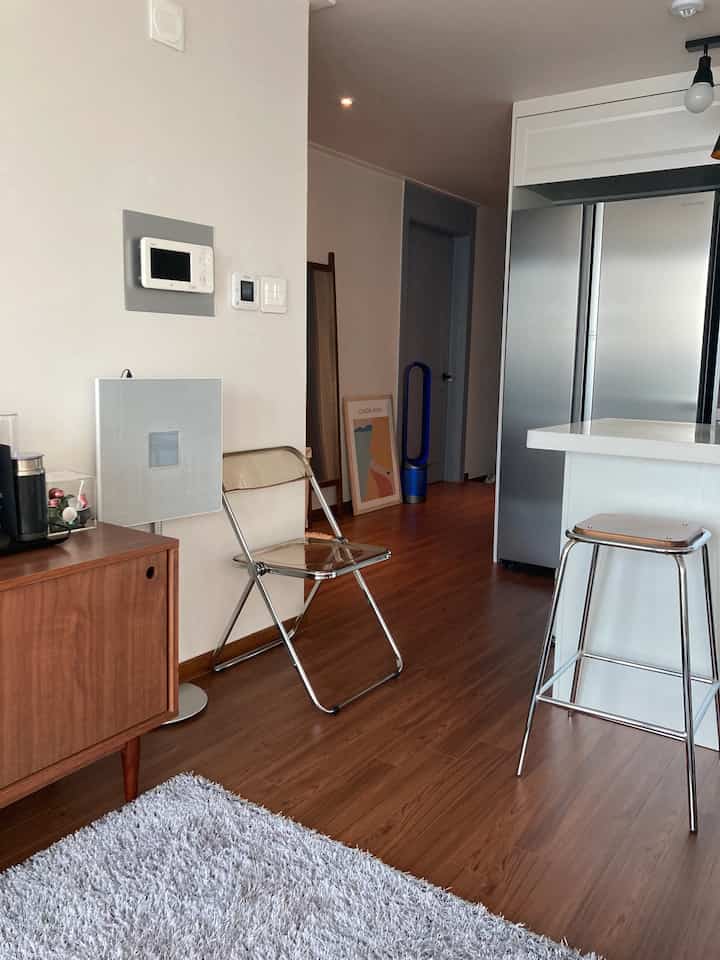 Natural wood tones and white dominate a 20-pyeong apartment kitchen and dining area featuring simple, compact interior design