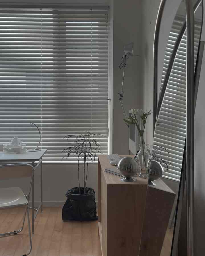 Minimal small home office in white and wood tones, featuring a clean desk and blinds with a calm atmosphere