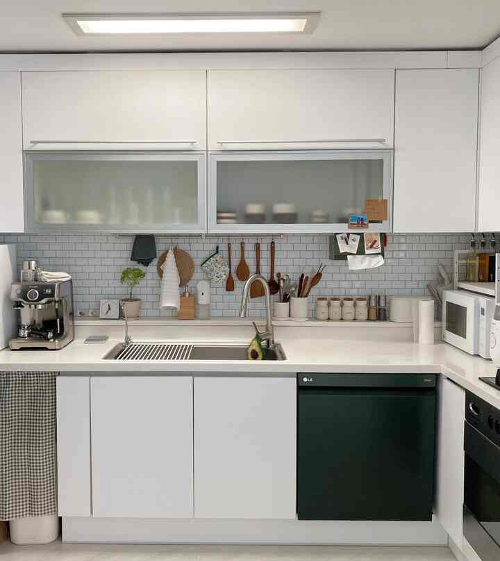 白とグレーのトーンのキッチン、コーヒーマシンと木製の調理器具が整然と配置されたモダンで清潔感のある空間