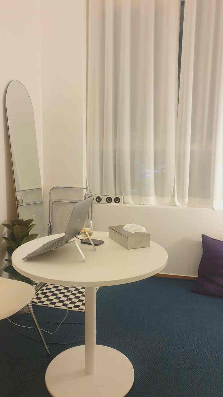 Soft white toned studio apartment with a round table and curtains, featuring a minimal and cozy atmosphere