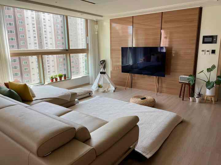 ホワイトと木目調が調和したリビング、広いソファと犬用のティピーが配置された雰囲気のある空間