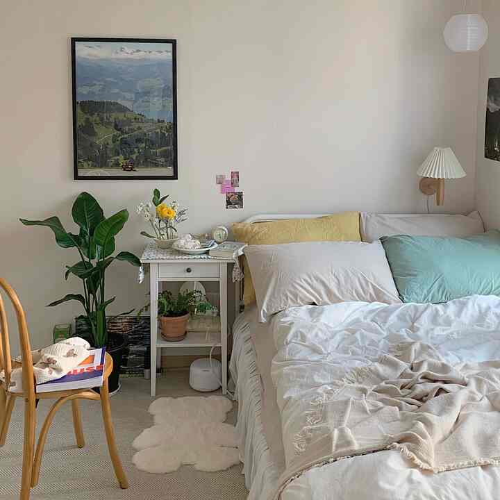 Bright white walls and natural wood elements frame a cozy bedroom bed with yellow and mint pillows