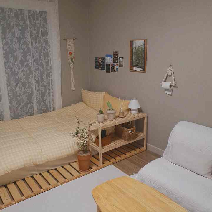 A beige and natural wood tone studio bedroom featuring cozy bedding and macrame decor in an emotional space