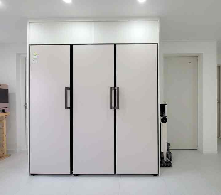 A modern kitchen space in white and natural tones featuring neatly arranged LG Objet Collection refrigerators