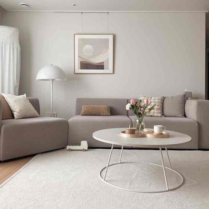 Beige and white tone living room featuring modular sofas and round low coffee table in a simple modern space