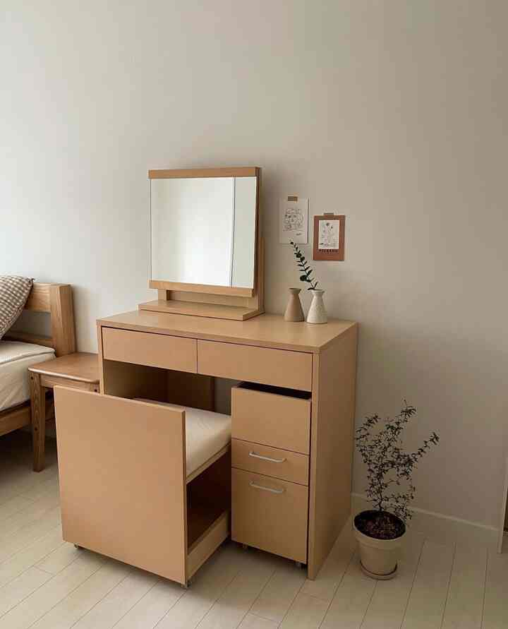 ナチュラルカラーのベージュの化粧台と植物が配置されたシンプルな寝室インテリア
