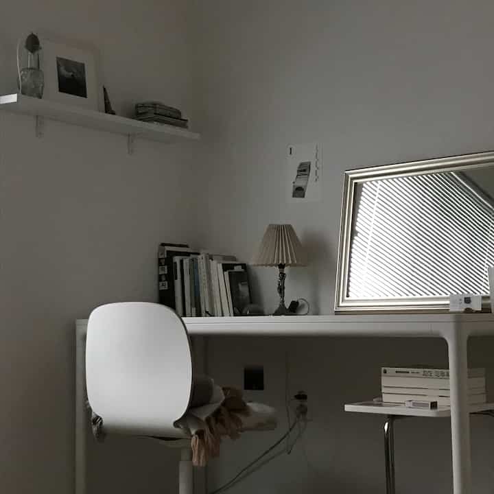 白とグレーのトーンのホームオフィス、白いデスクとチェア、きちんとしたレイアウトと本が配置されたシンプルなインテリア