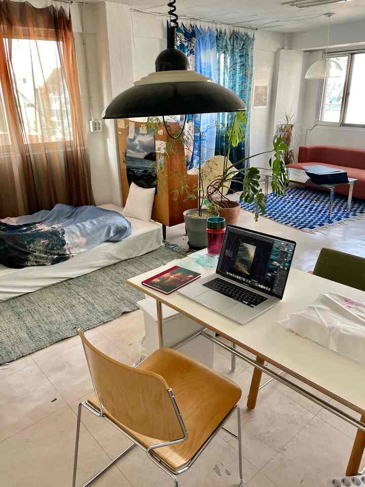 ブルーとブラウンのトーンのワンルーム、一人用ベッドとノートパソコンデスクが配置された居心地の良い在宅勤務空間