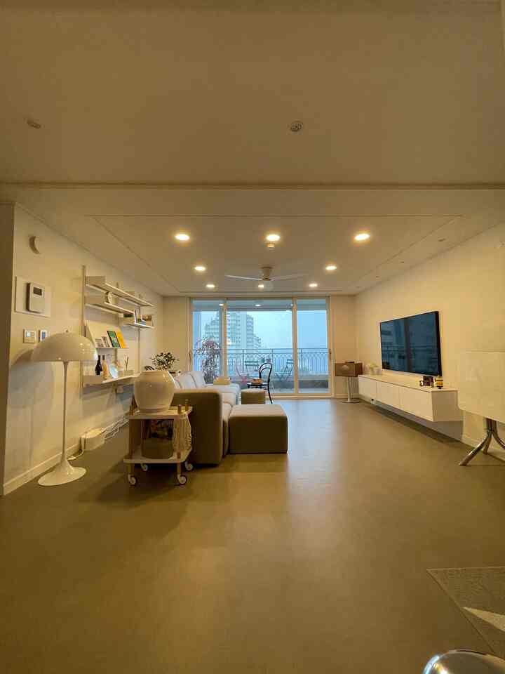 Beige and white toned living room featuring large sofa and floor lamp with modern natural atmosphere