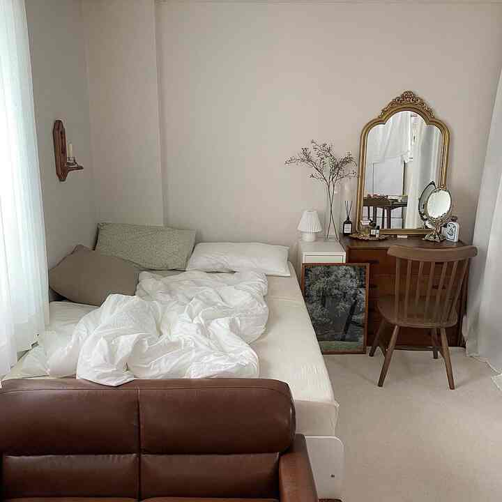 White and brown toned studio bedroom featuring vintage wooden dressing table and cozy bedding with a natural atmosphere