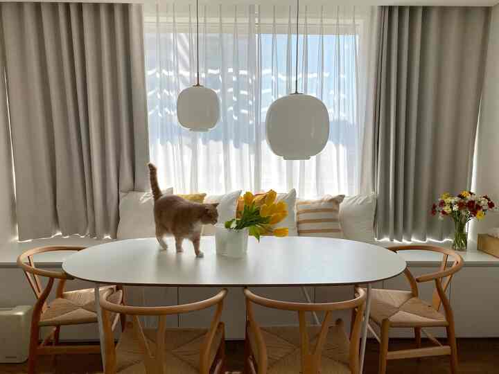 Bright living room in white and wood tones featuring a dining table, window seat, and warm natural decor