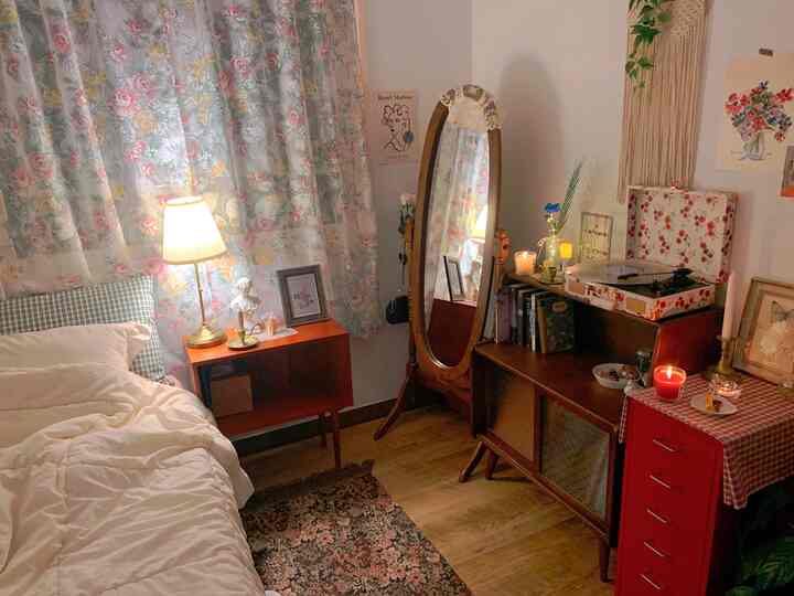 暖かい照明のフロアランプとヴィンテージ木目調家具が配置された居心地の良い小さな寝室