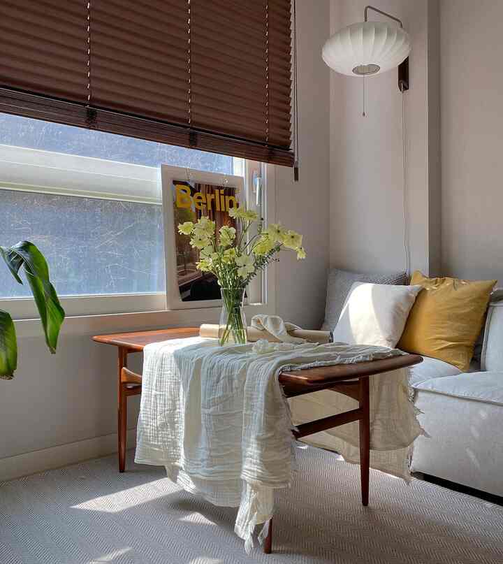 Bright white and brown-toned living room featuring a wooden sofa table, white sofa, and a Berlin poster by the window for a cozy atmosphere