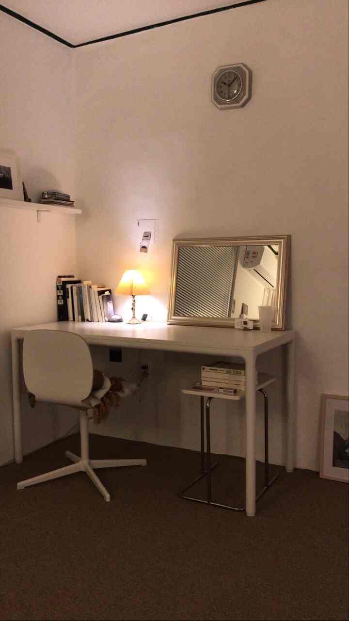 A simple and natural home office space in white and brown tones, featuring a desk, chair, and warm table lamp lighting