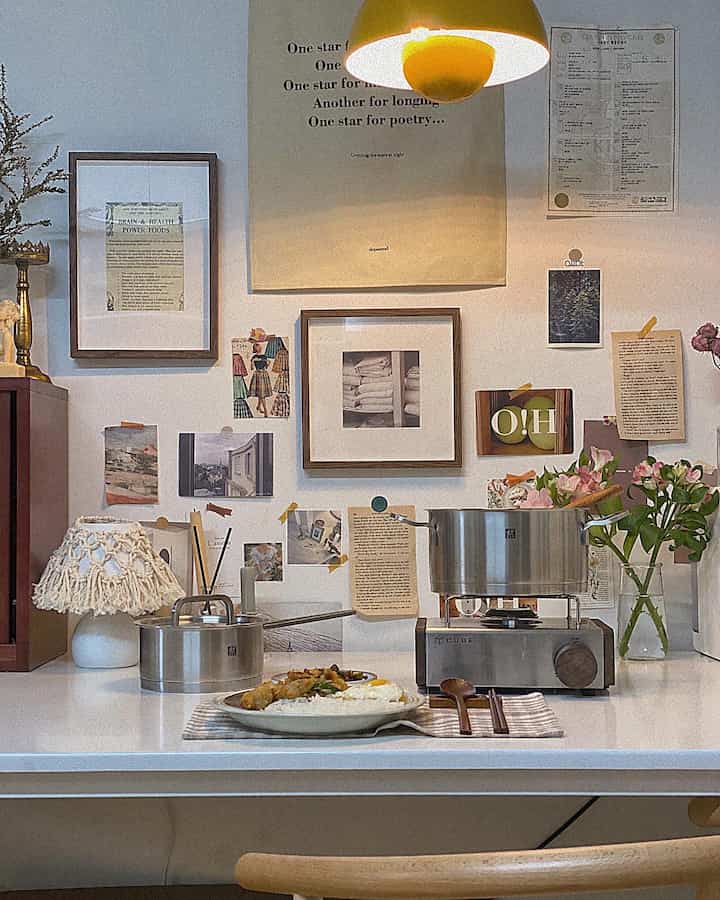 Cozy kitchen space featuring white and wood tones, vintage kitchen utensils, wall decor, and a yellow pendant light