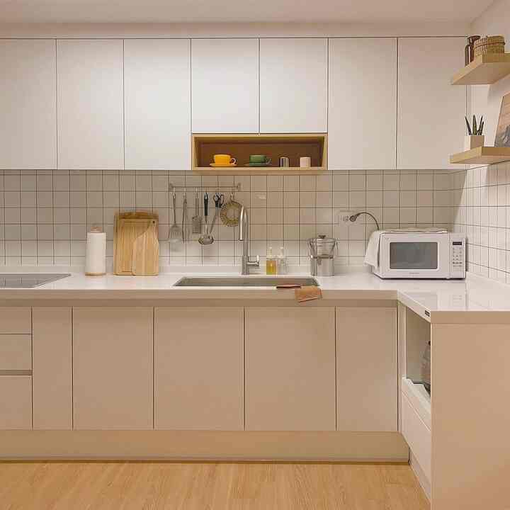 Clean kitchen in white and wood tones featuring practical storage and simple design