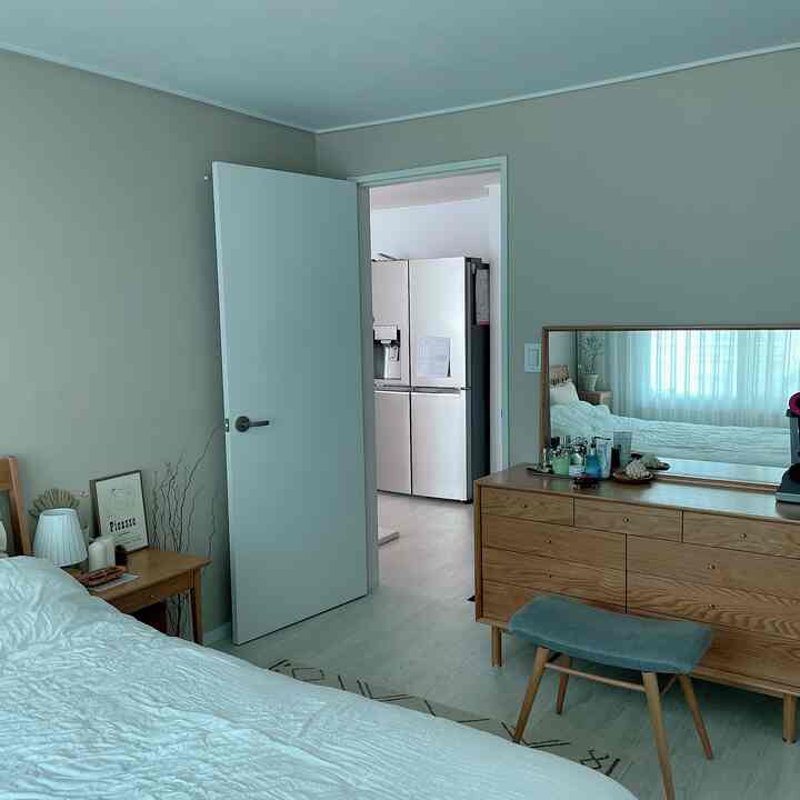 ベージュの壁と白い寝具が調和した約6畳のナチュラルモダンな寝室の雰囲気あるインテリア