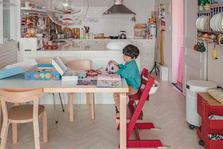 明るいナチュラルな色調のキッチンダイニング、赤いハイチェアに座る子供がいる雰囲気のあるインテリア