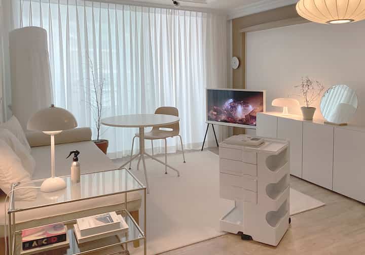 White-toned living room featuring a storage trolley and simple furniture arranged neatly creating a clean atmosphere
