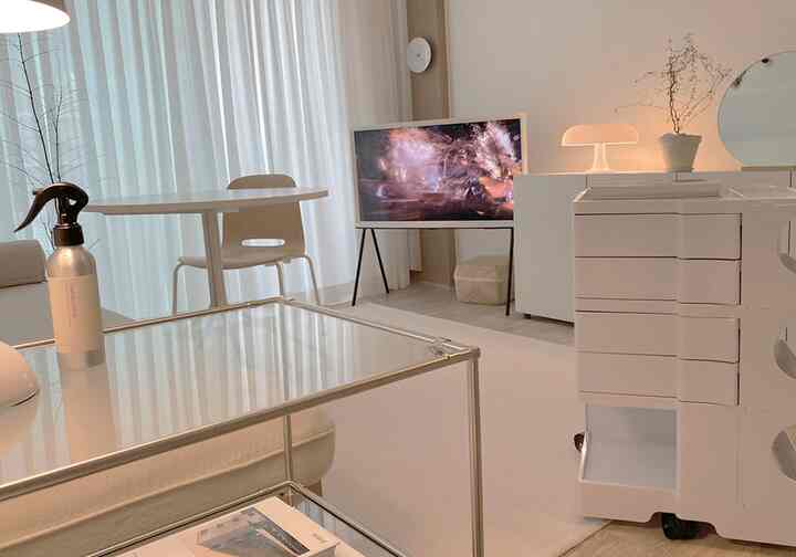Bright white-toned living room featuring a round dining table and modular dresser arranged in a modern style