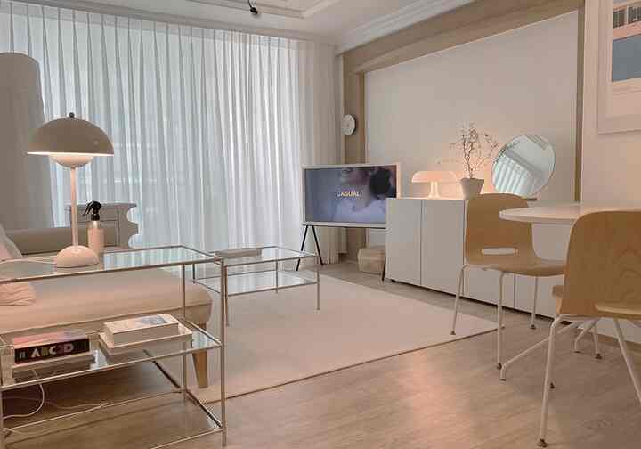 White and natural tone living room featuring clean sofa, sheer curtains, and minimal table lamps creating a cozy atmosphere