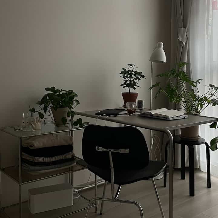 白とナチュラルカラーのホームオフィス、机と棚に植物が配置された、すっきりとして広々としたレイアウトの空間