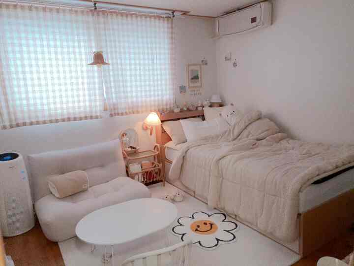 Beige-toned natural wood bedroom for single occupant featuring wall sconce, checkered curtains, and smiley flower rug creating a cozy atmosphere