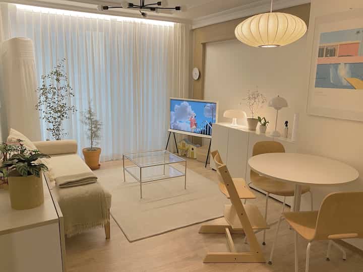 White and beige living room featuring round dining table, sofa bed, and natural cozy atmosphere