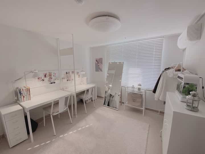 White-toned kids' room for two daughters, featuring dual desks and chairs, blinds, and storage units in a clean modern style