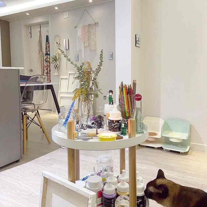 Bright white and wood-tone home workspace featuring a central tray with art supplies and a cat in a cozy atmosphere