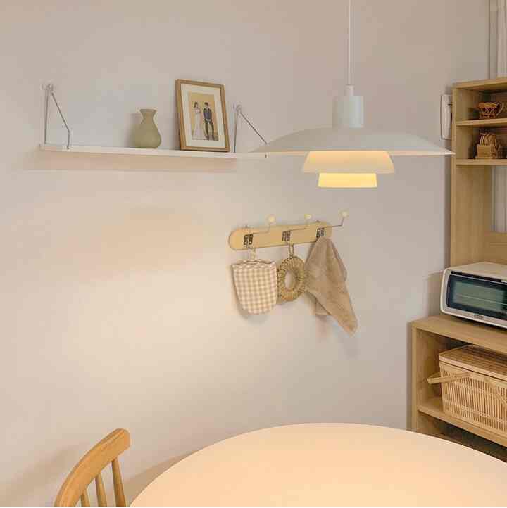 Beige and wood tone two-person dining space featuring a round table and coat rack shelf with warm, practical ambiance