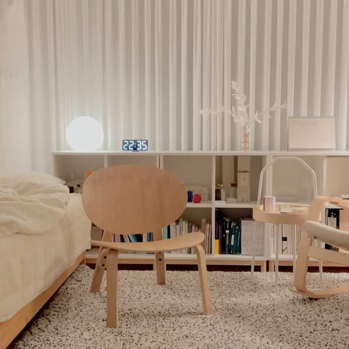 White and natural-toned bedroom featuring wooden chairs and rug in a simple, cozy space