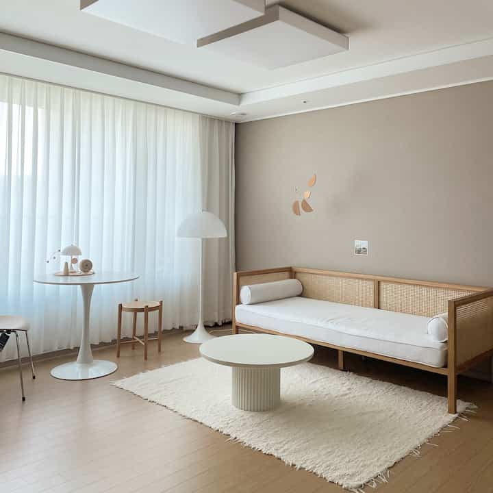Beige and white toned living room featuring rattan sofa and round table in a natural modern style space