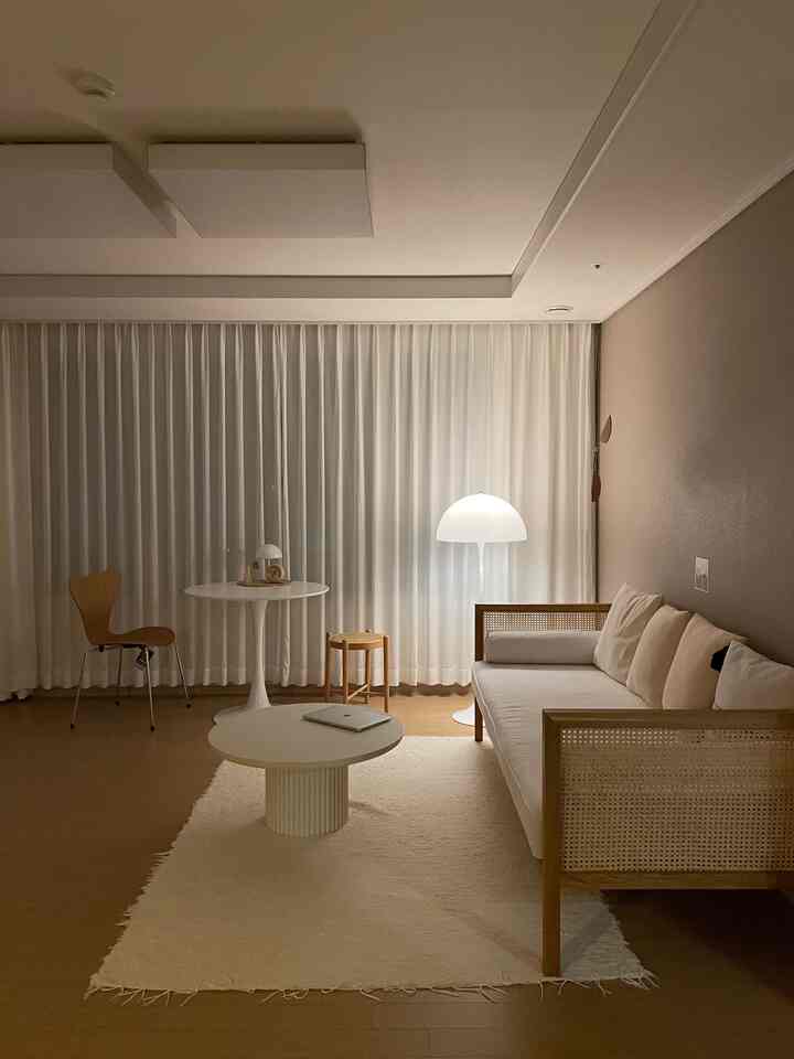 Natural style living room with dominant white and wood tones, featuring simple furniture and warm ambient lighting creating a cozy atmosphere