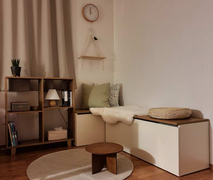 Wood tone and white living room featuring corner storage bench and round coffee table in a simple natural style