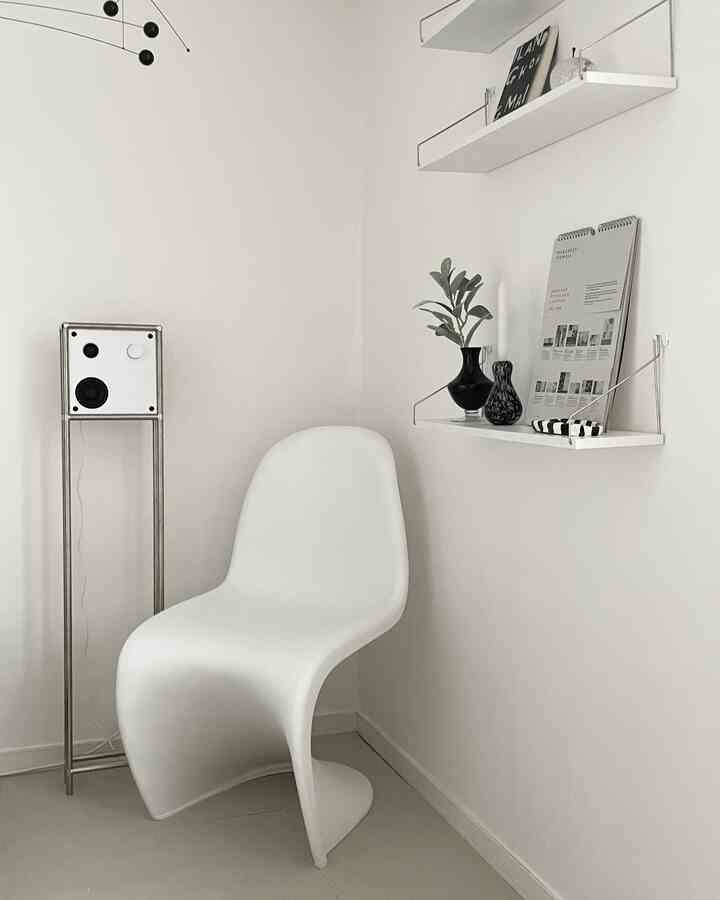 白色のトーンでまとめられたモダンでシンプルな空間、白いチェアとスピーカー、壁に設置された棚が特徴的なインテリア