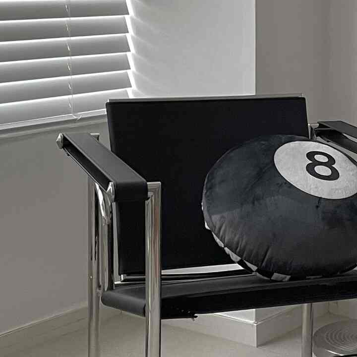 Modern entrance area in a natural white and black palette, featuring an armchair with an eight-ball cushion, creating a clean atmosphere