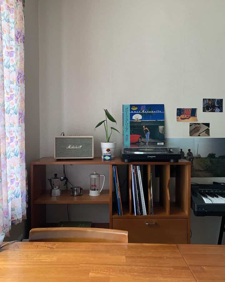 Natural wood-tone living room featuring a mid-century modern LP cabinet with turntable, wooden dining table and chairs creating a cozy atmosphere