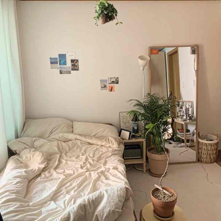 ホワイトと木目調の寝室、アレカヤシの植物と大きな全身鏡が配置された、落ち着いた自然な雰囲気のインテリア