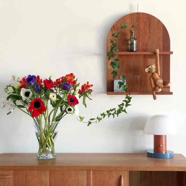 Natural brown-toned living room featuring a vase with colorful flowers and wooden monkey figurine offering a cozy atmosphere