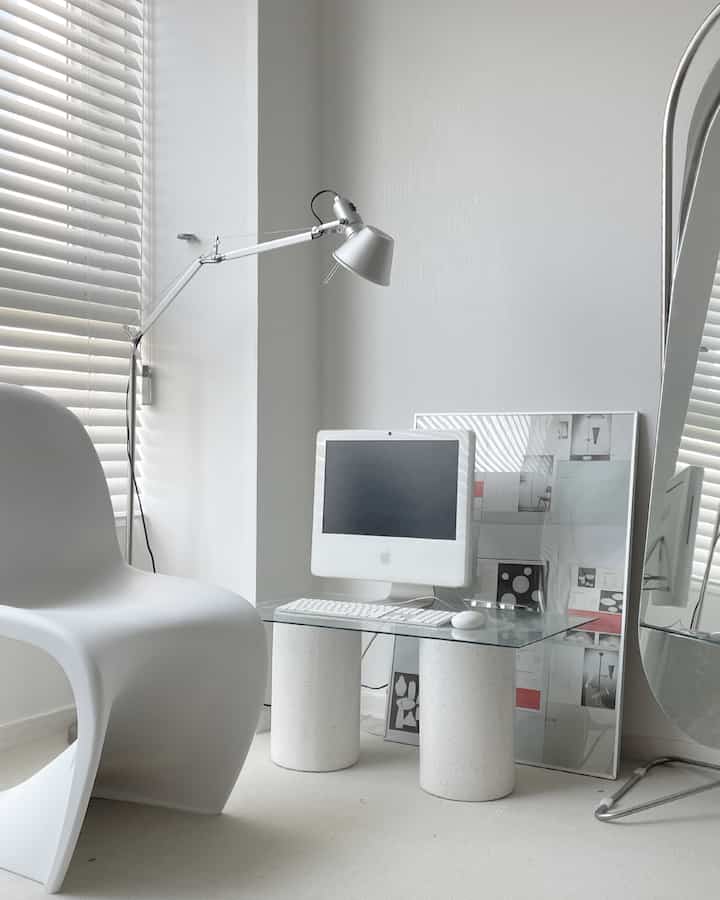White and silver-toned studio apartment home office featuring a transparent desk and modern chair with a clean atmosphere