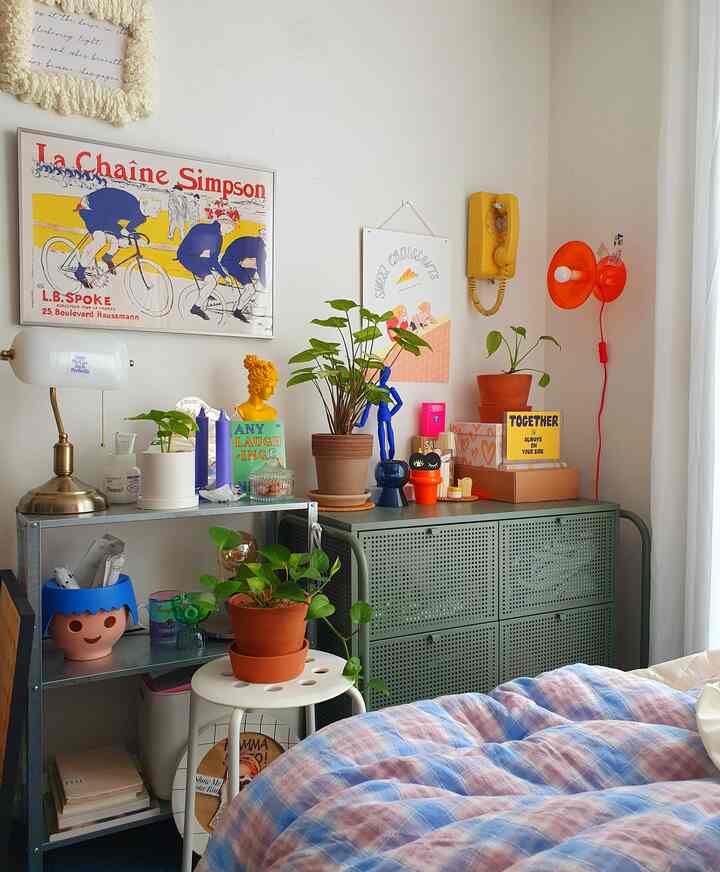 Bright bedroom with white walls and green storage cabinet, decorated with various plants and vintage accessories for cozy ambiance