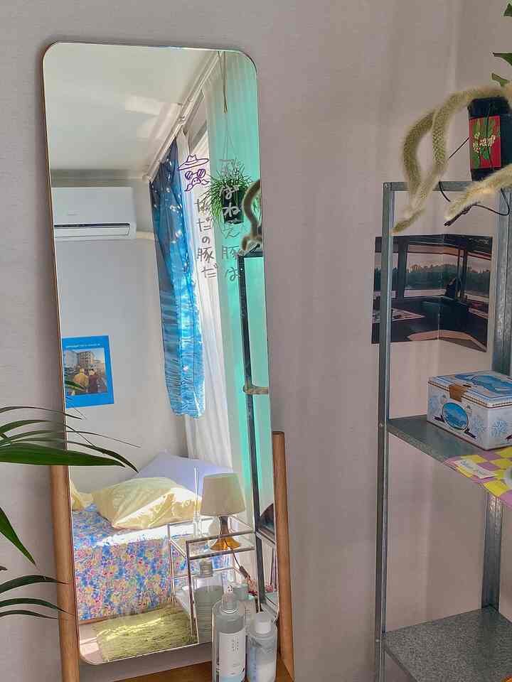 Natural beige-toned bedroom featuring a wooden frame mirror, vintage floral bedding, and warm lighting creating a cozy atmosphere