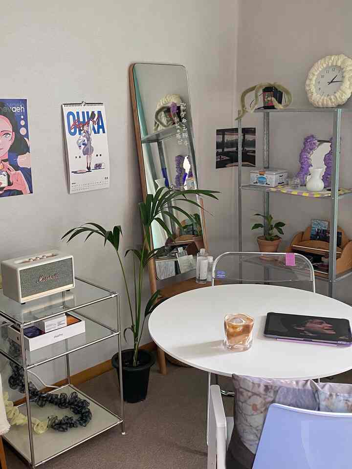 白色を基調としたワンルーム、丸テーブルと椅子、植物と棚が配置された雰囲気のあるヴィンテージスタイルのインテリア