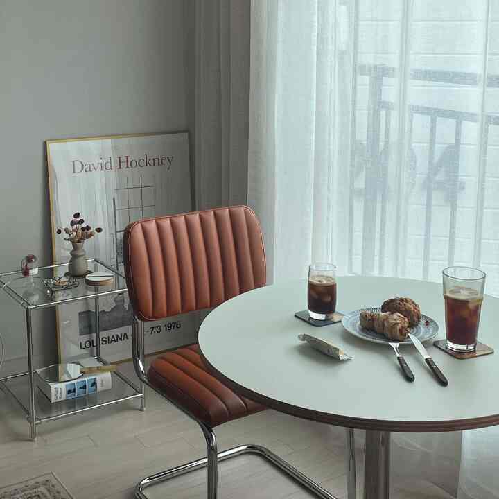 White and brown toned dining room featuring a round table and vintage-style chair in a cozy home cafe setting
